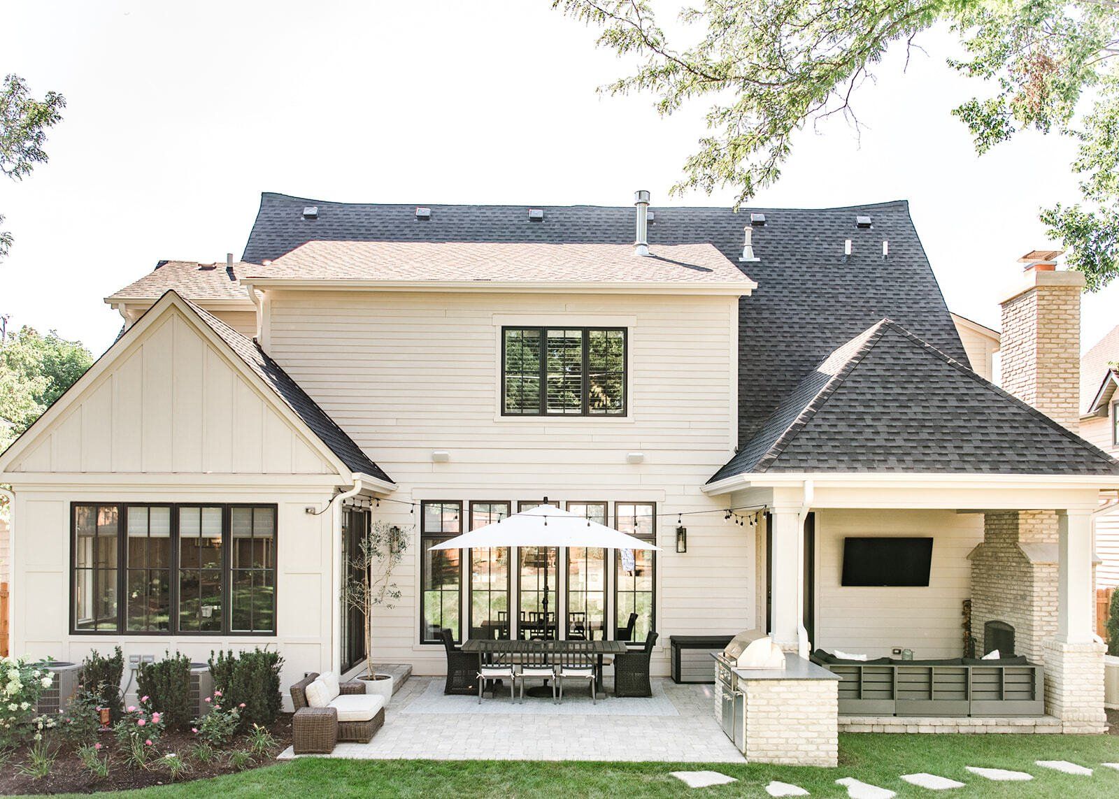 The back of a white house with a black roof and a patio area.