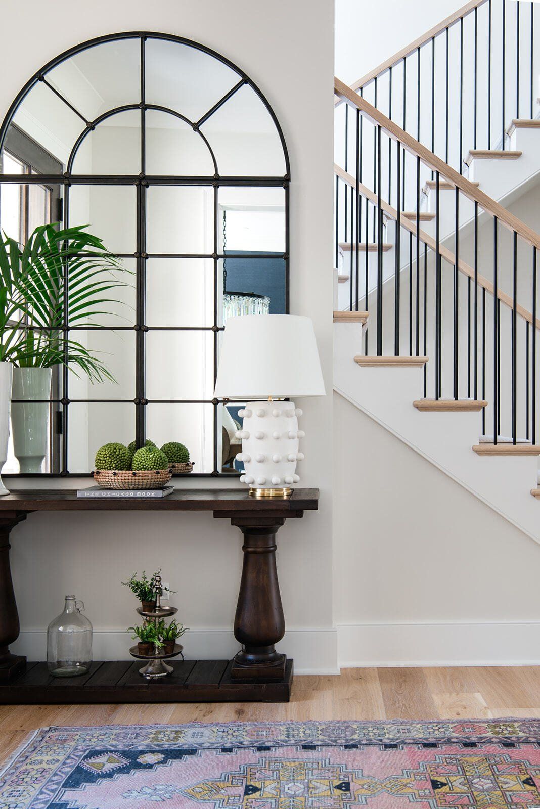 There is a staircase in the background and a large mirror on the wall.