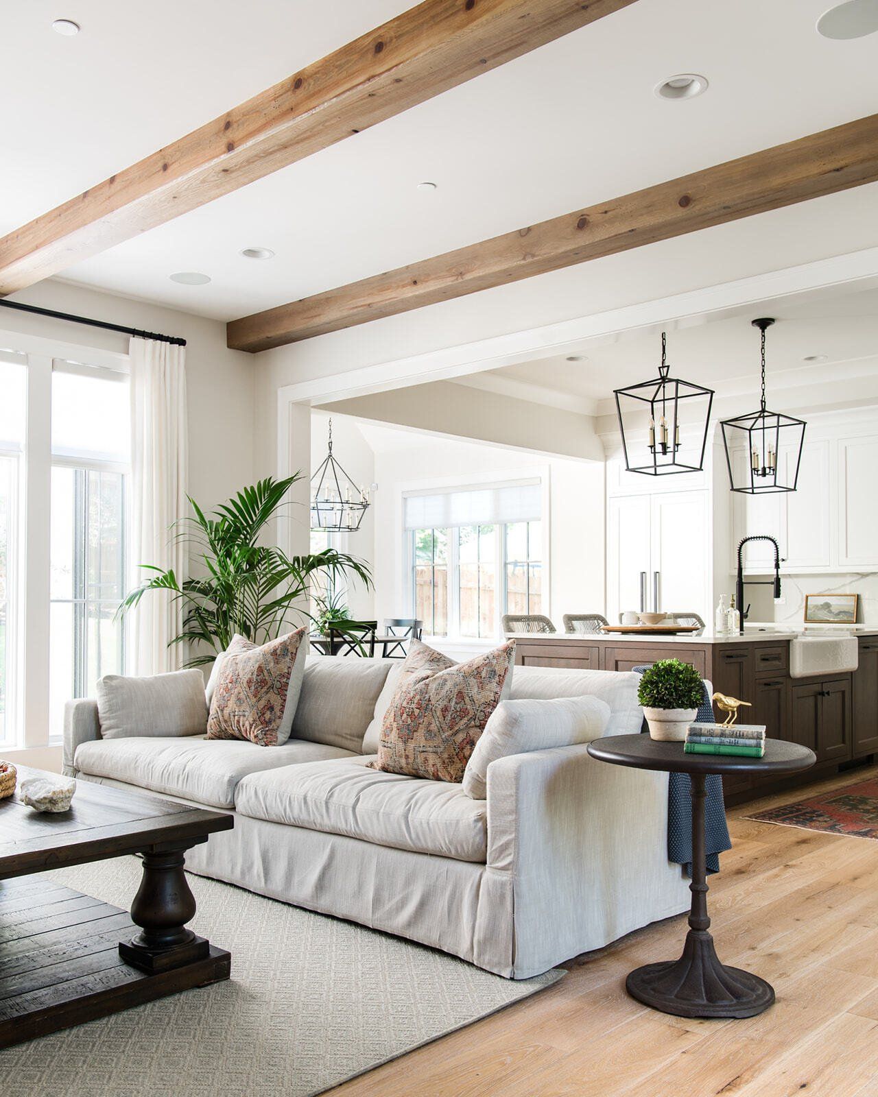 A living room with a couch , coffee table , and wooden beams.
