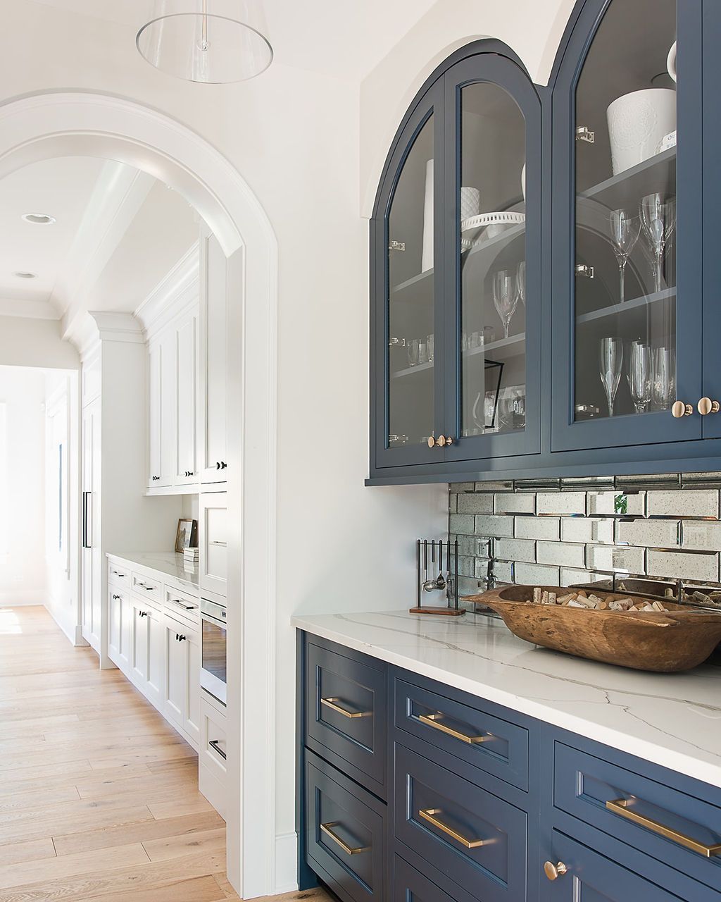 Blue and white kitchen with arched cabinets and a marble countertop.