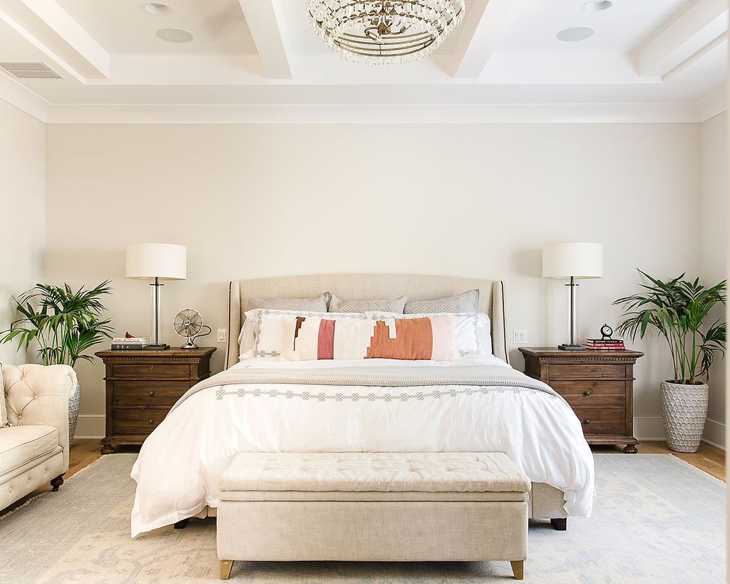 Spacious bedroom with a large bed, nightstands, lamps, a bench, and a sofa.