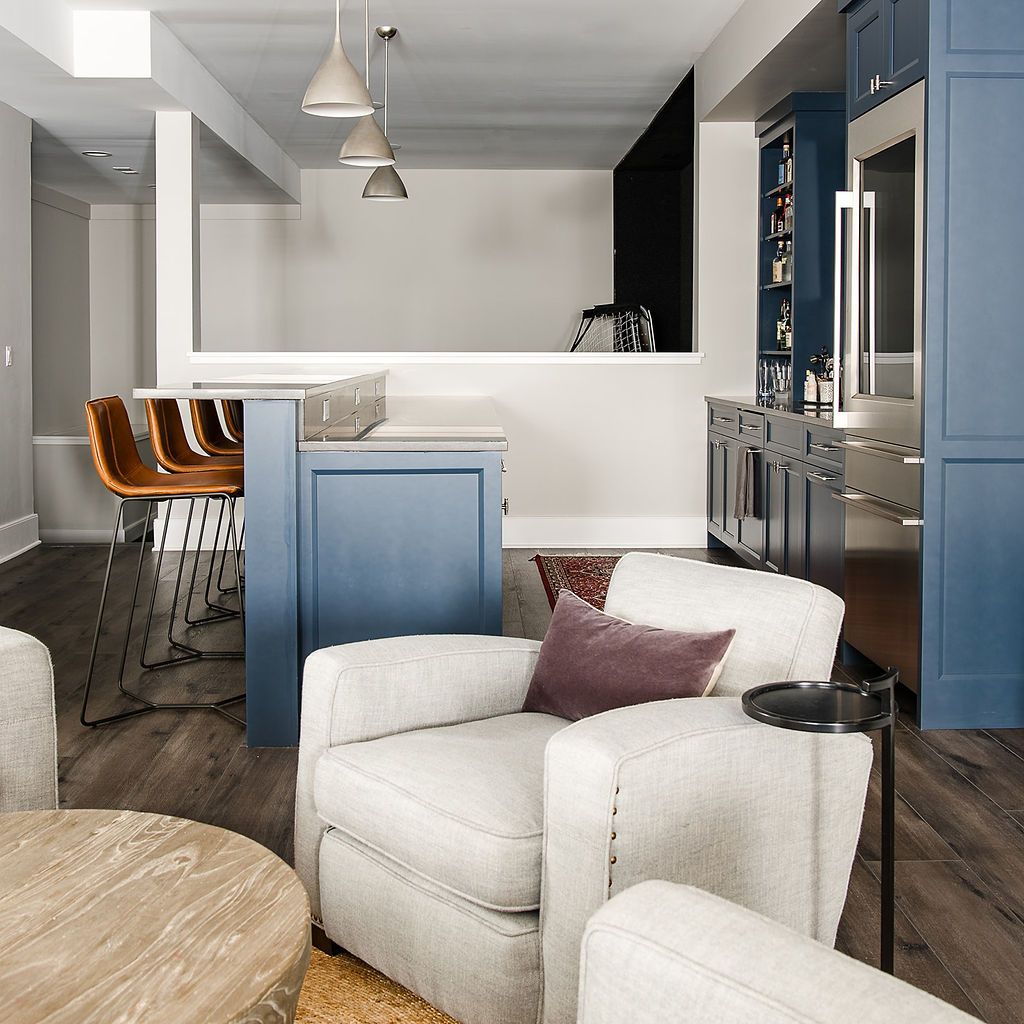 Cozy living space with blue cabinets, bar stools, white armchairs, and a round wooden coffee table.