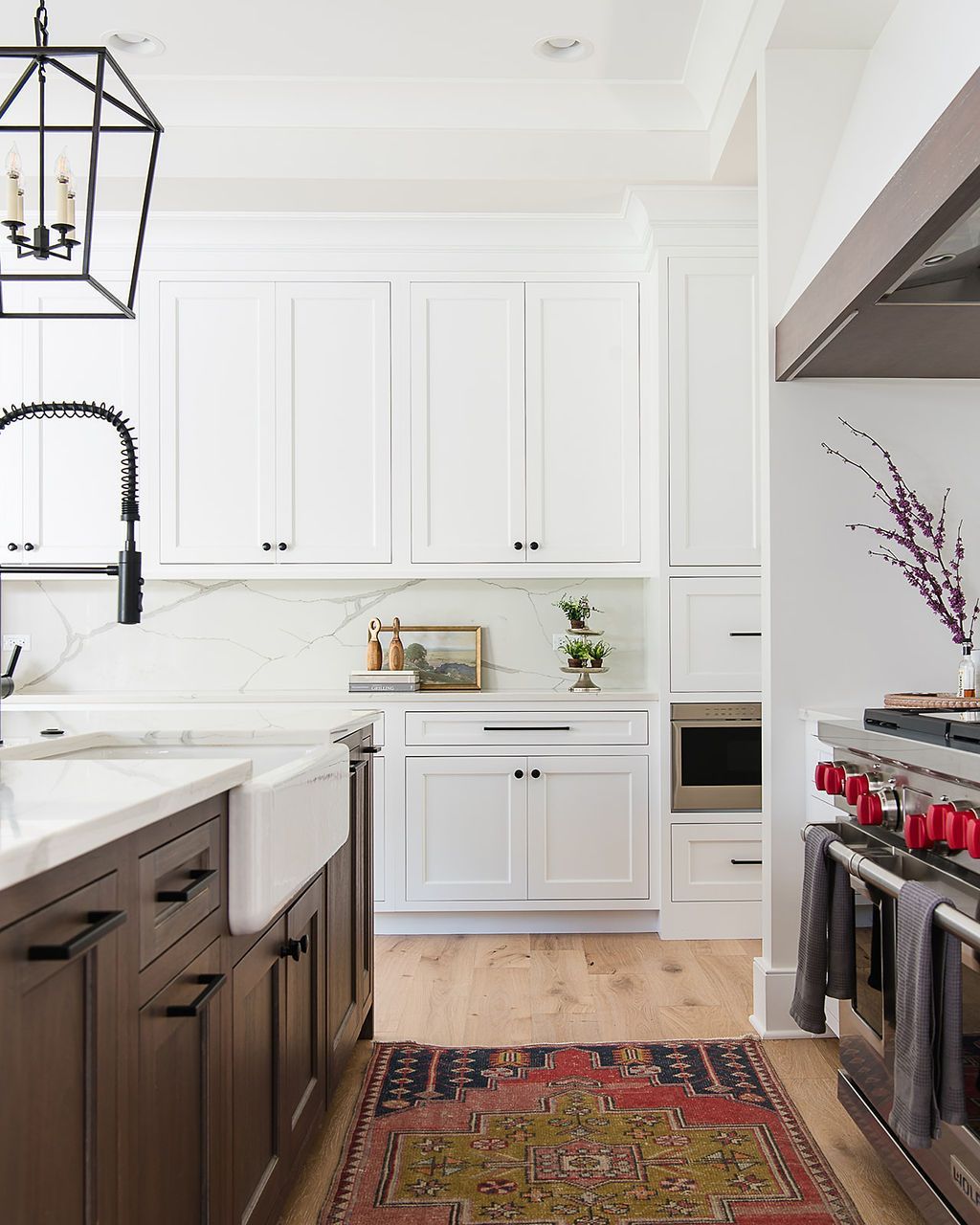 Kitchen with white cabinets, dark island, and red patterned rug.