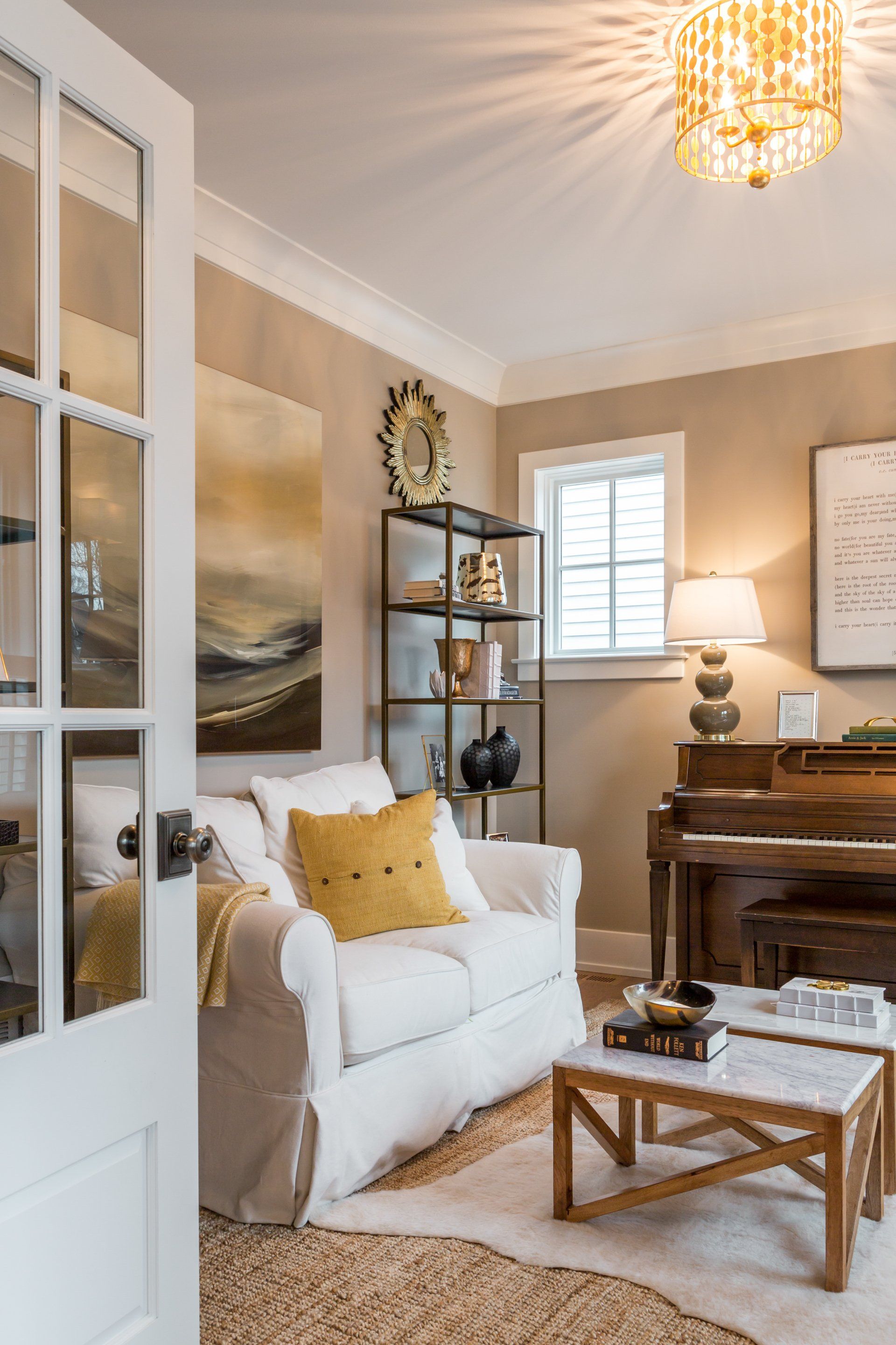 A living room with a couch , chair , coffee table and piano.