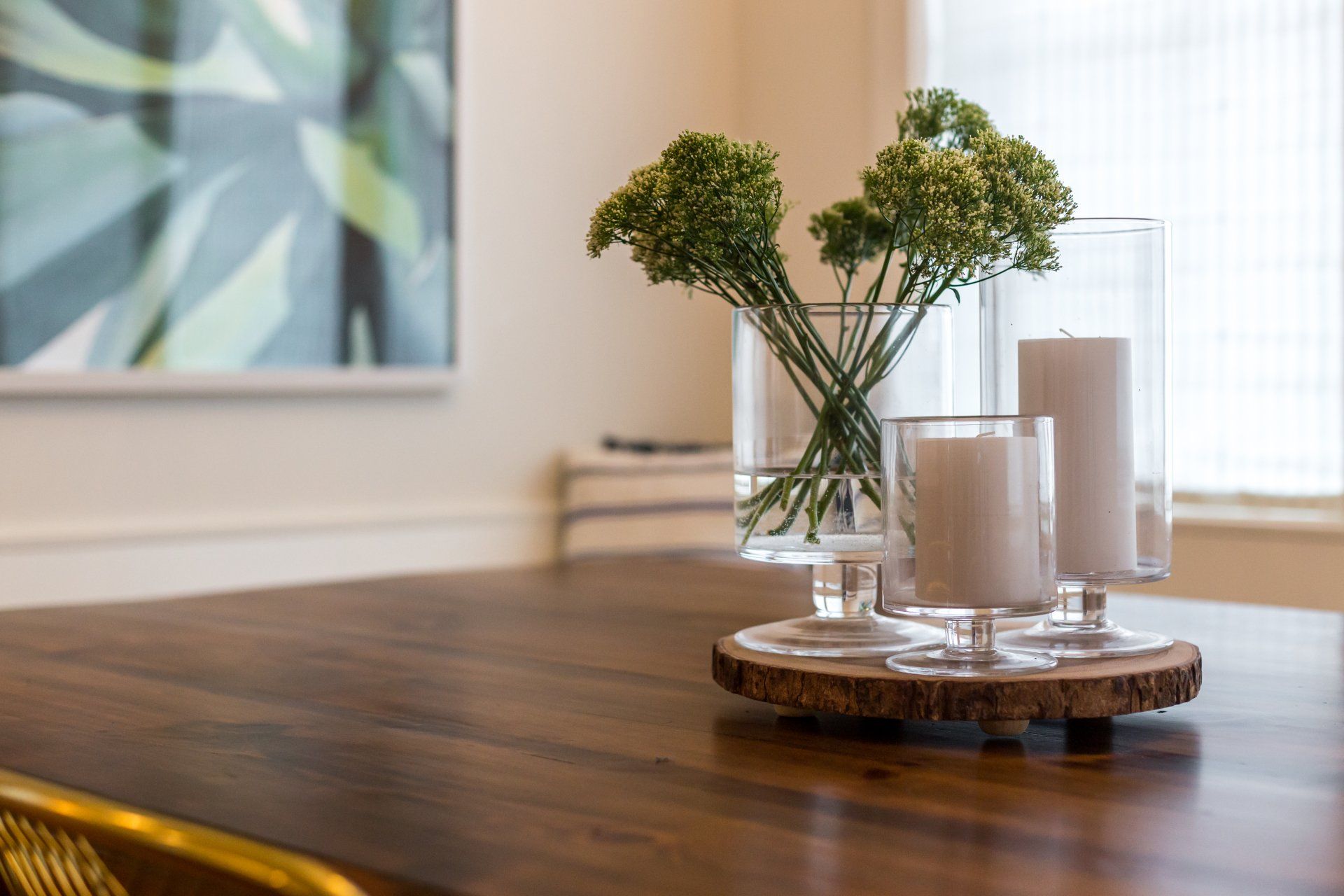 A wooden table with a vase of flowers and candles on it.