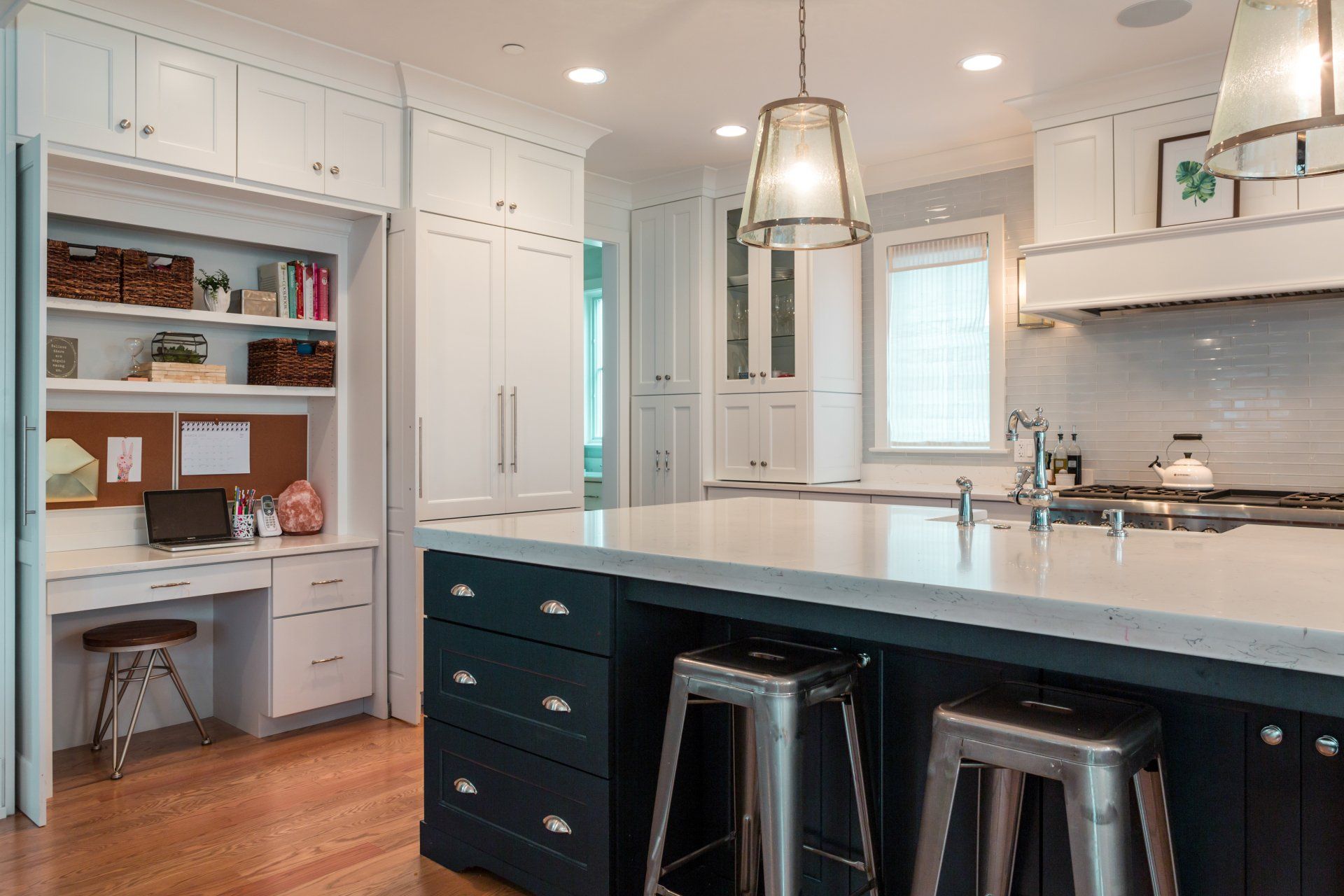 A kitchen with a large island , stools and a desk.