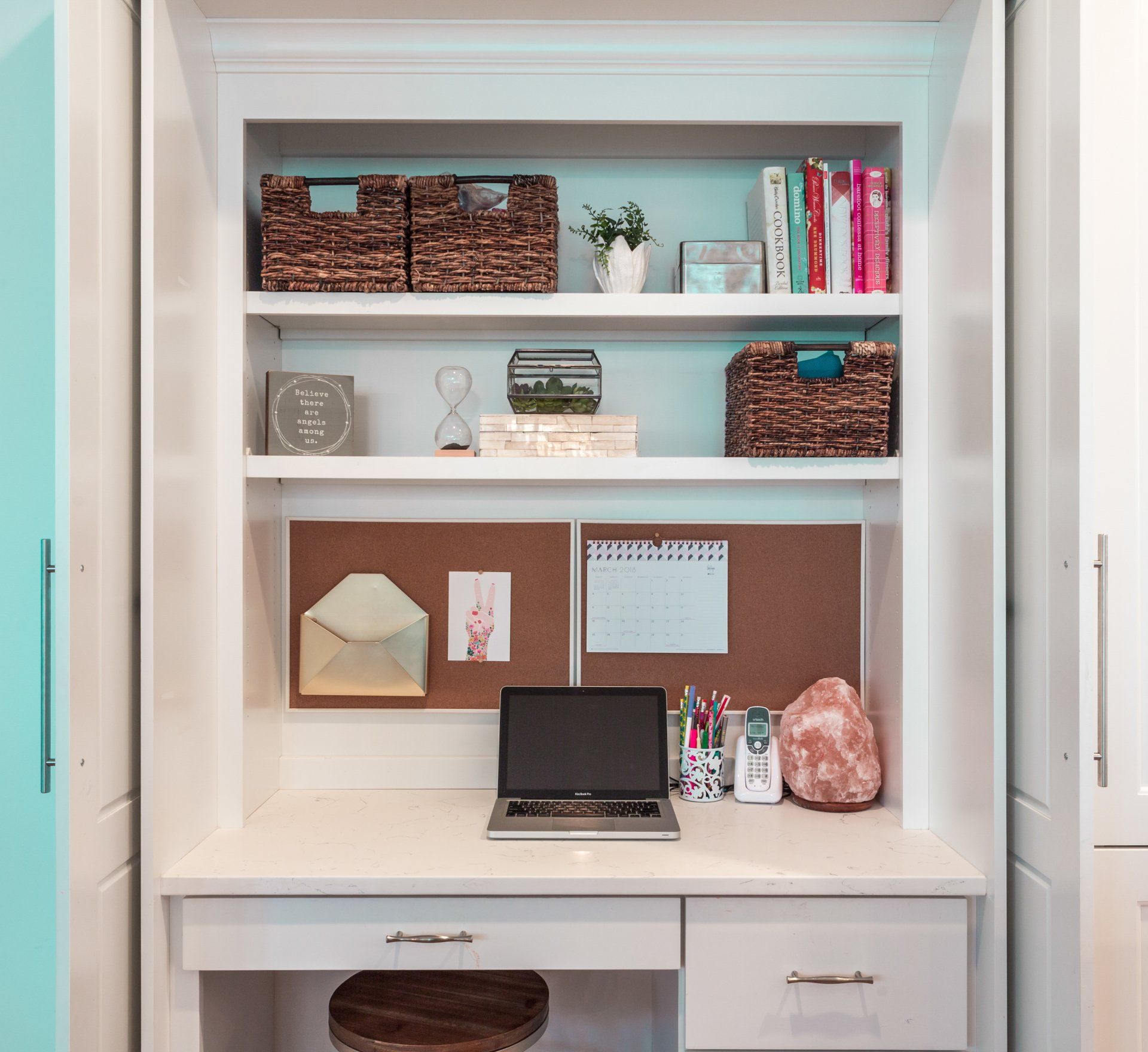 A laptop computer is sitting on a desk in a closet.