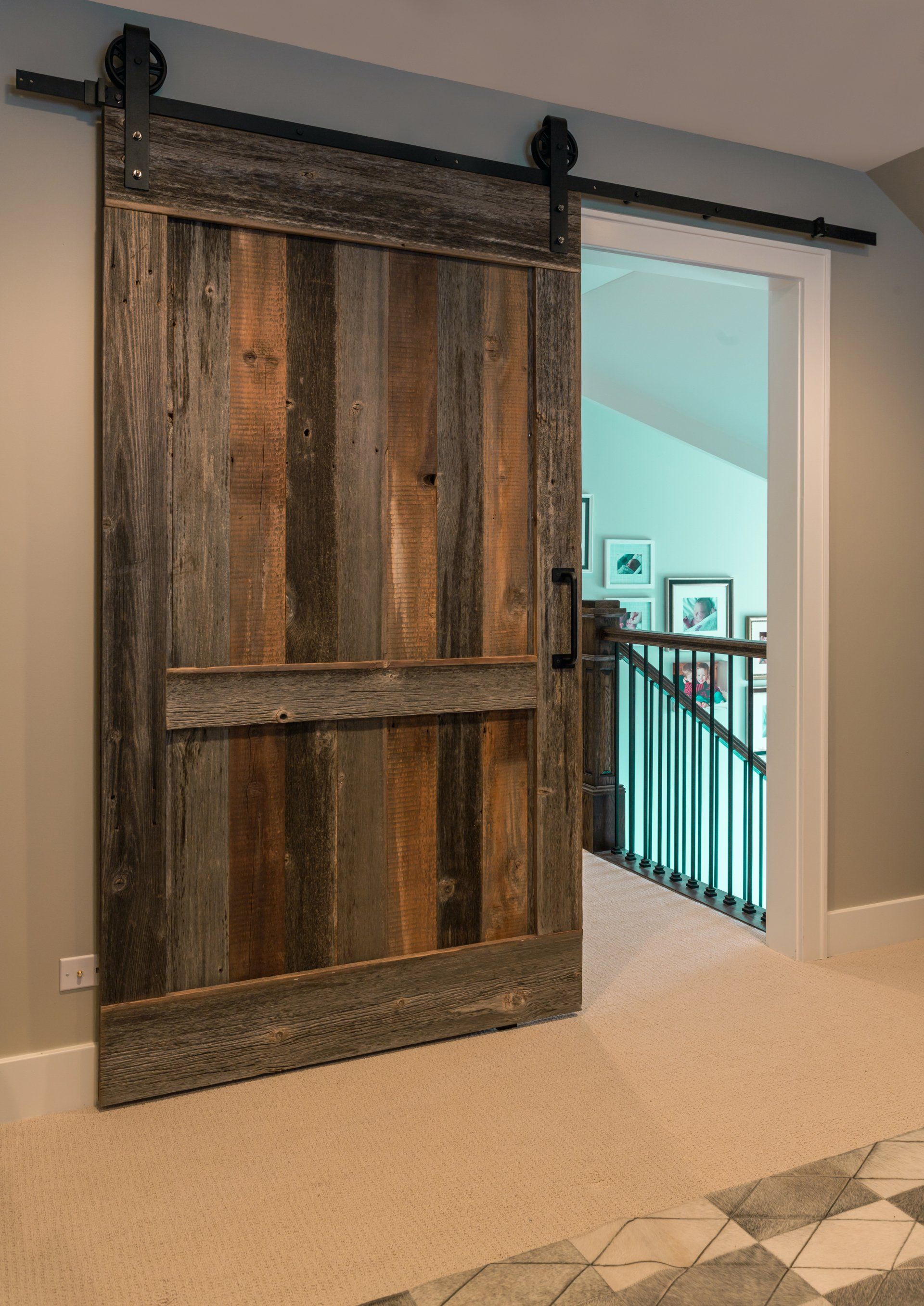 A wooden sliding barn door is open in a hallway leading to a staircase.
