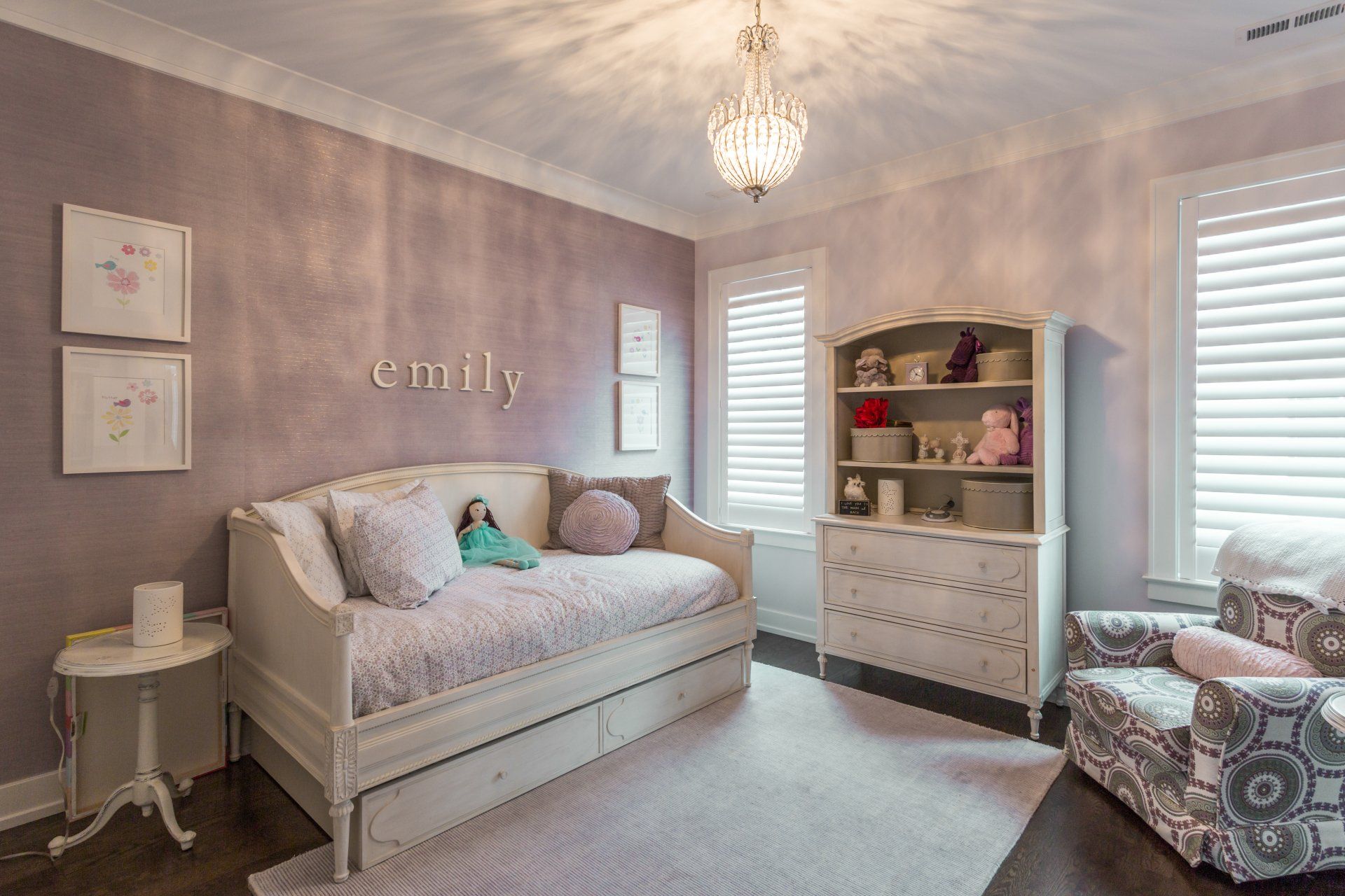 A bedroom with a day bed , dresser , chair , and chandelier.