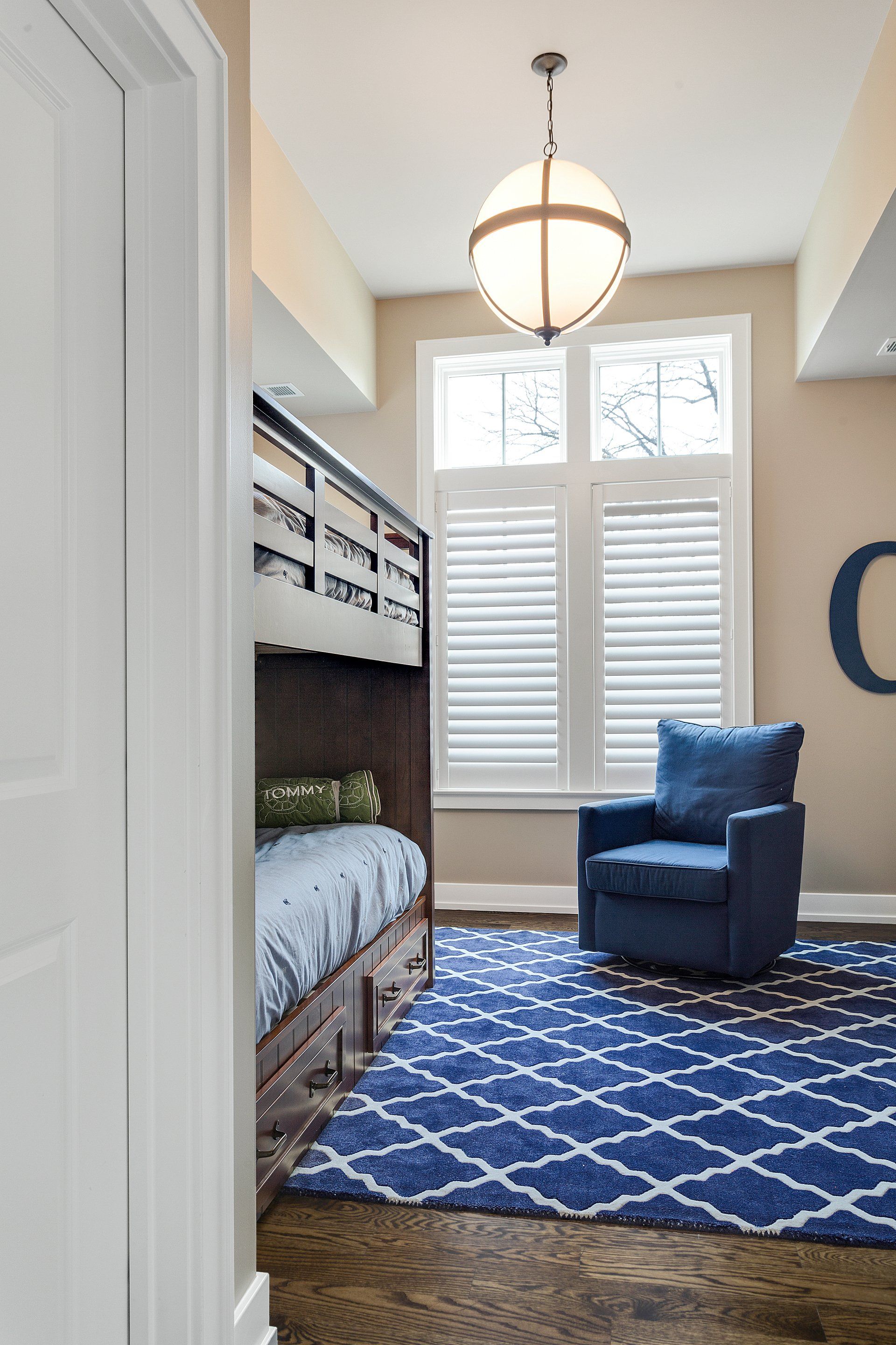 A bedroom with bunk beds , a blue chair and a blue rug.