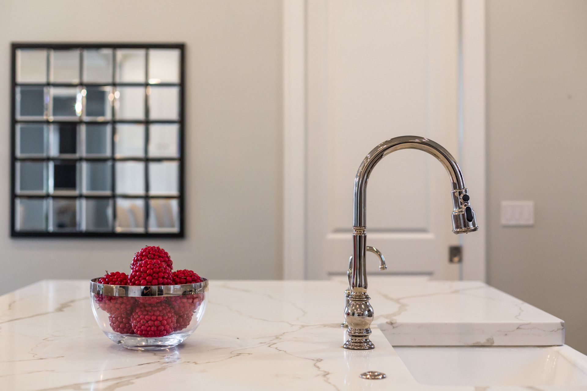 A bowl of raspberries is sitting on a kitchen counter next to a sink.