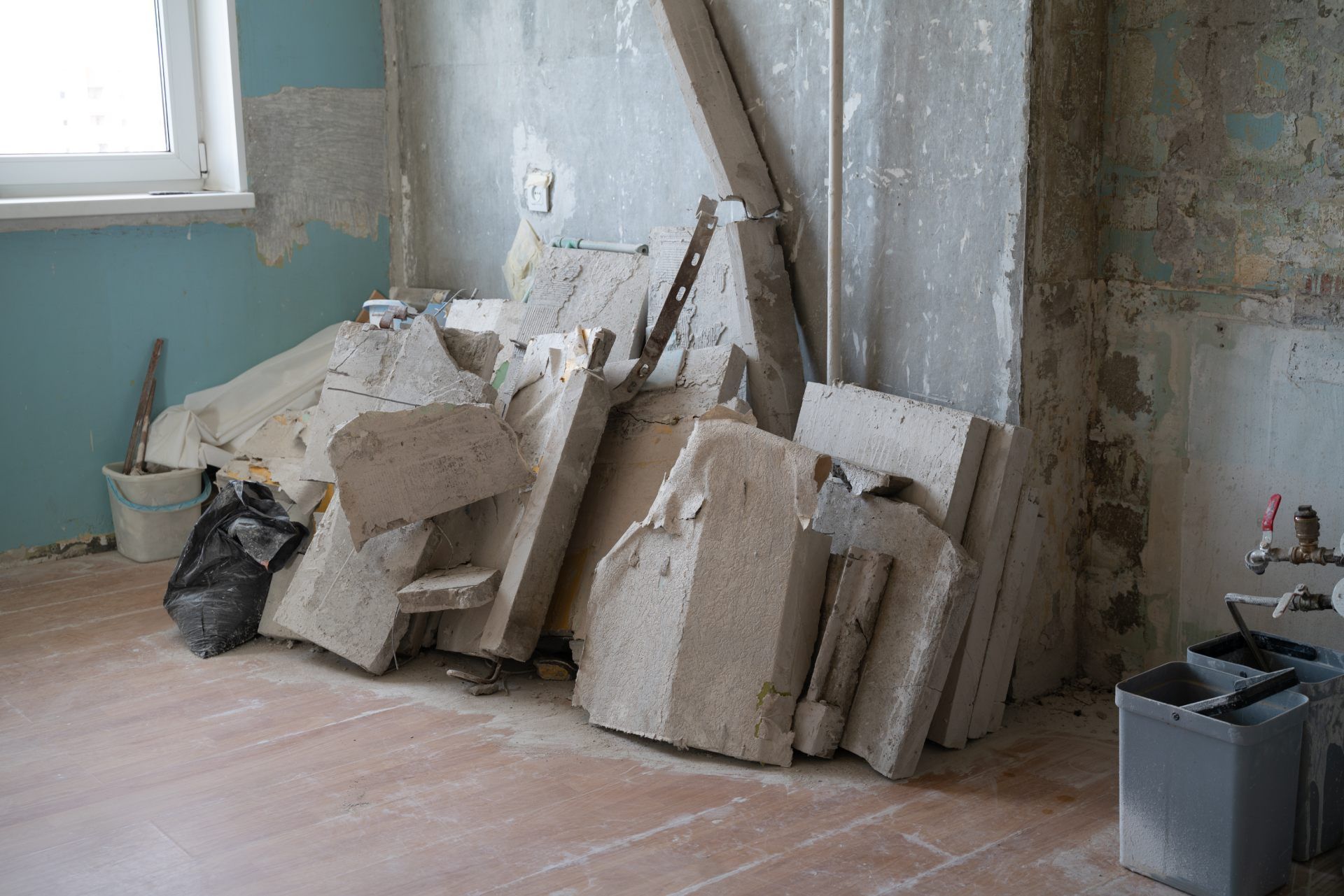 Construction debris and large concrete slabs piled on the floor of a room undergoing renovation.