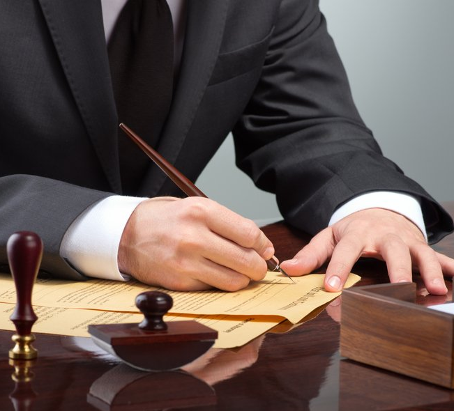 A man in a suit and tie is writing on a piece of paper