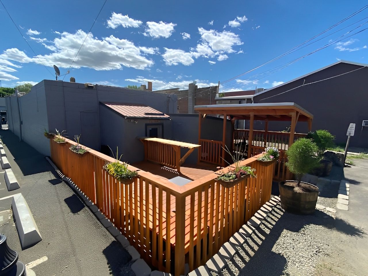 A wooden deck is surrounded by a wooden fence in front of a building.