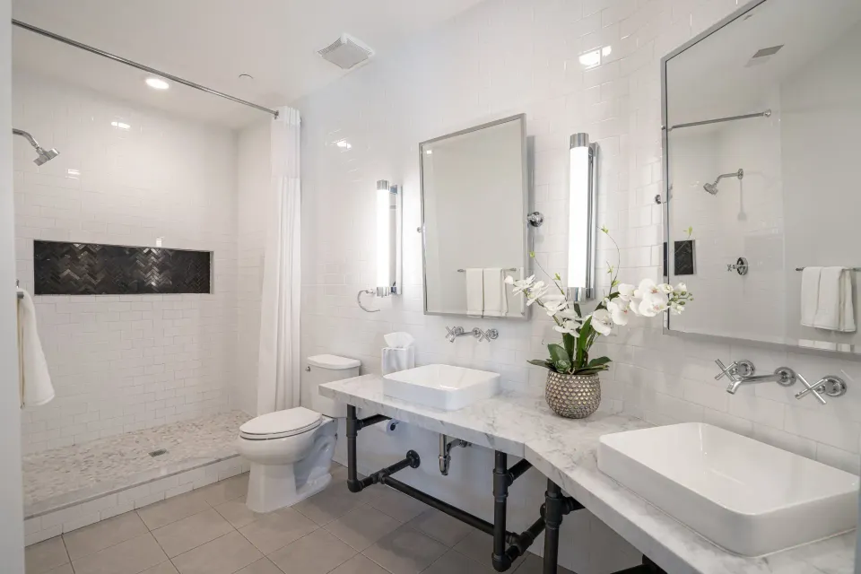 A bathroom with two sinks , a toilet , and a shower.