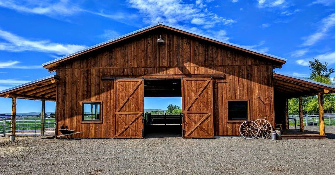 A large wooden barn with sliding doors and a porch.