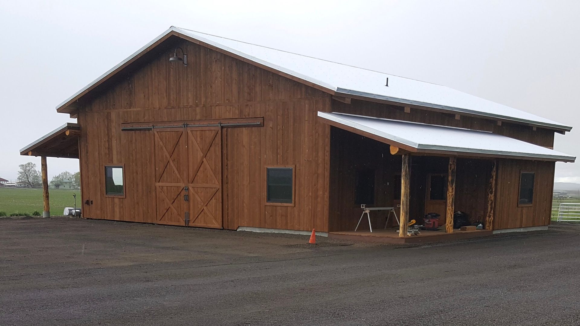 A large wooden barn with a porch and a white roof