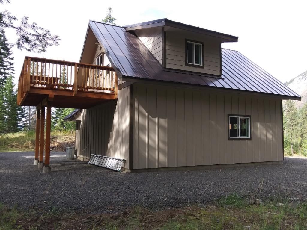 A small house with a metal roof and a wooden deck