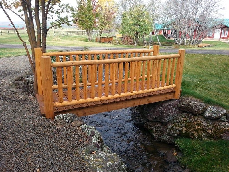 A wooden bridge over a stream in a park