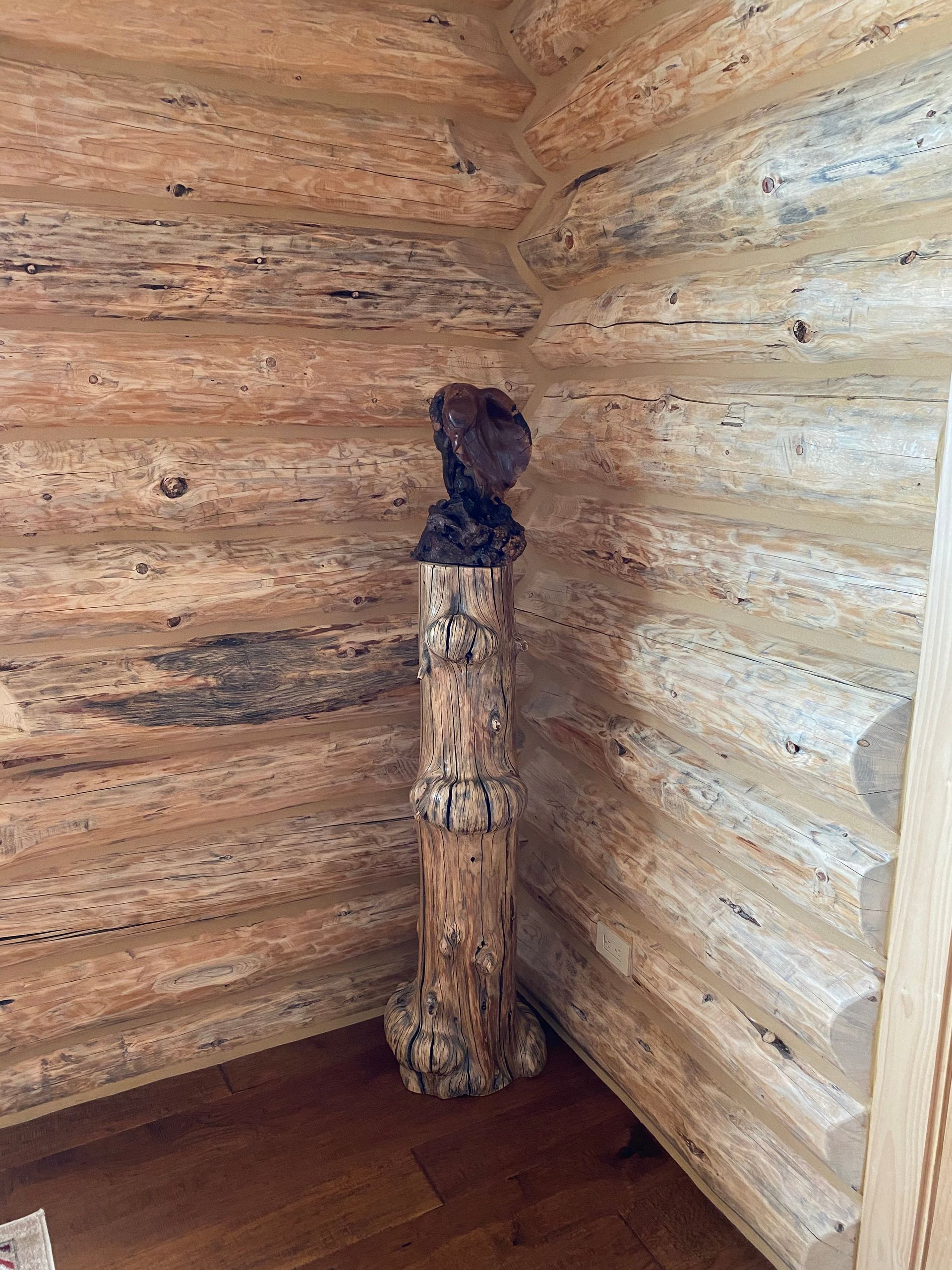 A wooden pole is sitting in the corner of a log cabin.