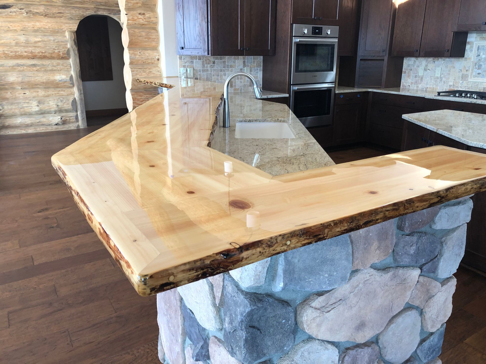 A kitchen with a wooden counter top and a stone island.
