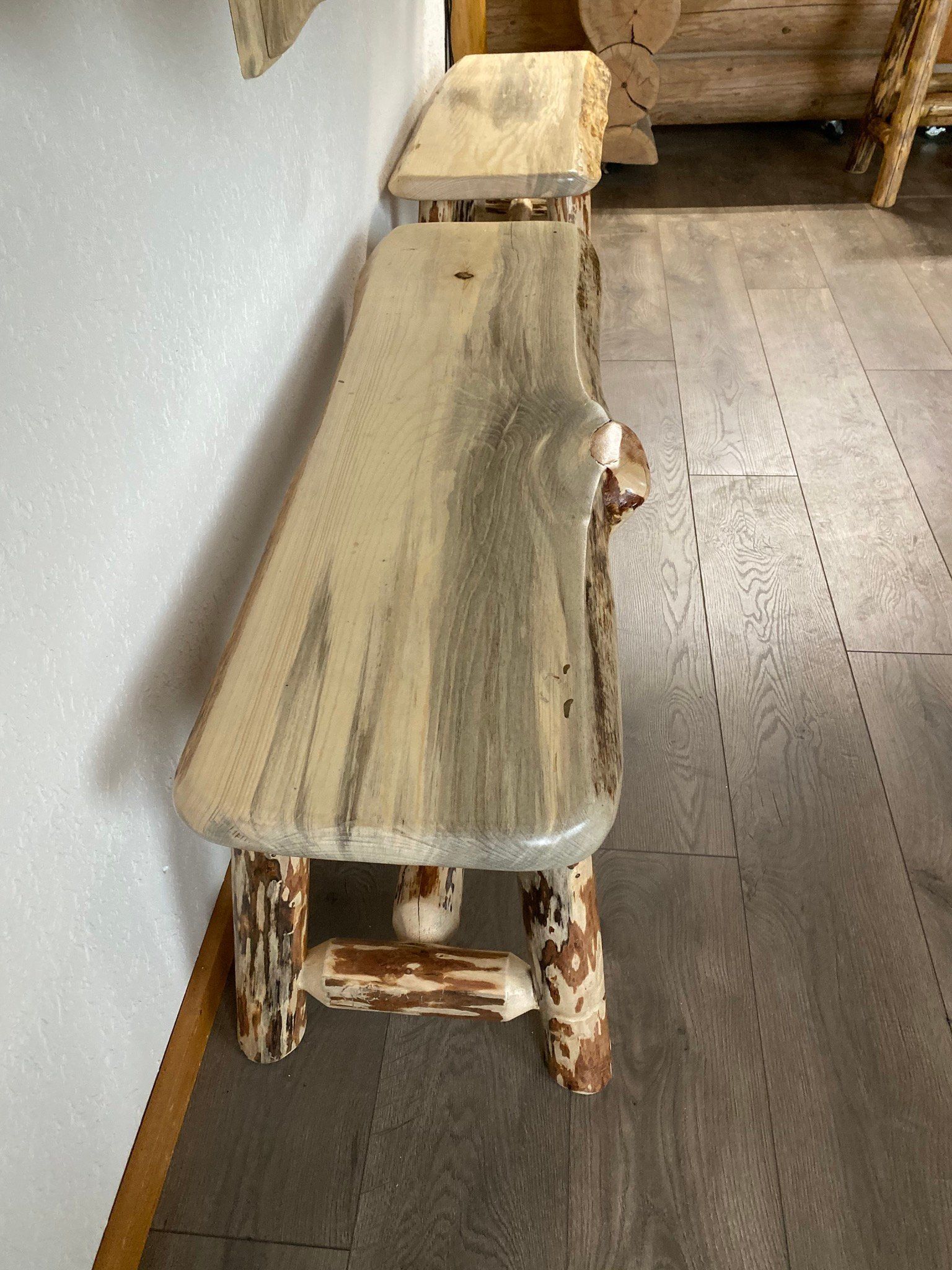 A wooden bench is sitting in a hallway next to a wall.