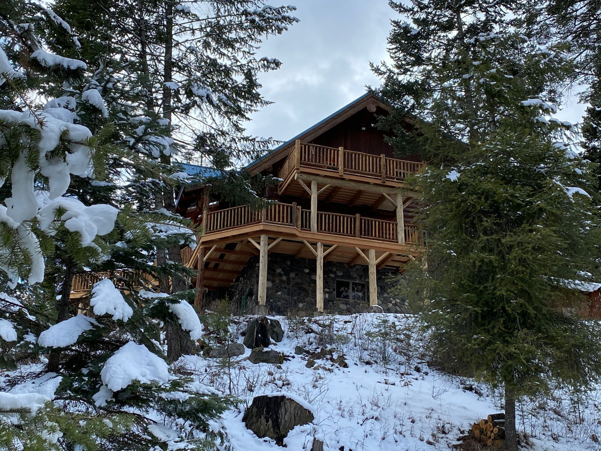 A large log cabin is surrounded by snow covered trees.