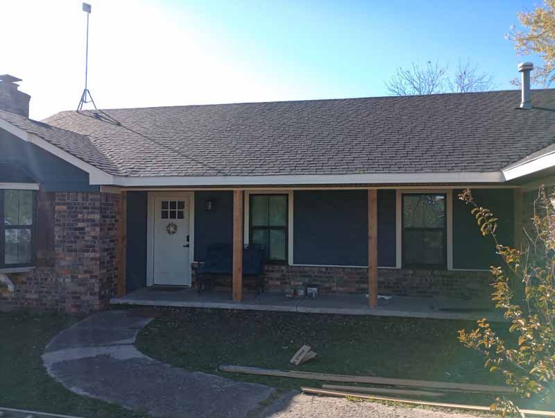 A brick and blue-sided house with a porch and curved walkway.