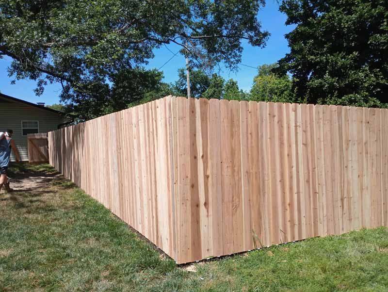 Wooden fence bordering a grassy yard, under a bright blue sky.