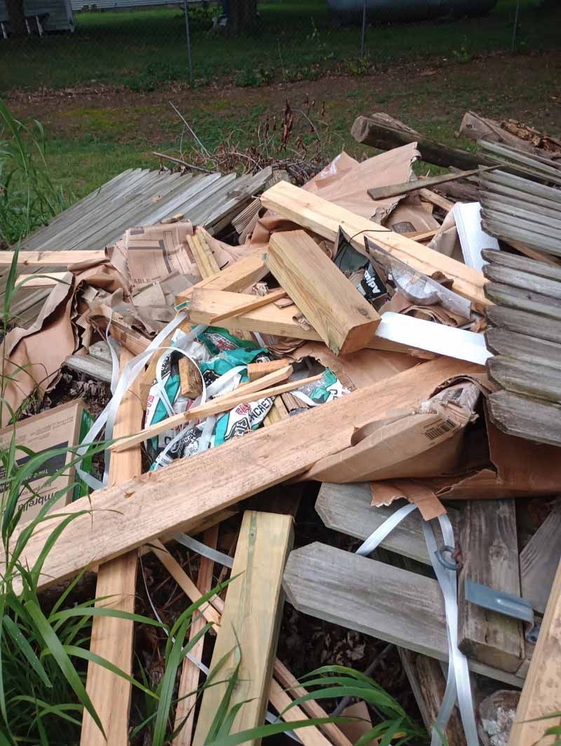 Pile of scrap wood, including boards, slats, and possibly roofing material, outdoors.