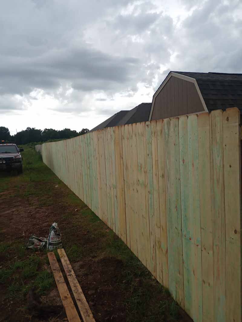 Wooden fence along a grassy area, overcast sky.