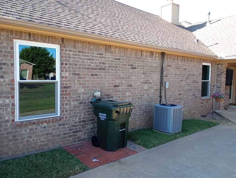 Brick building exterior with window, trash can, and AC unit.