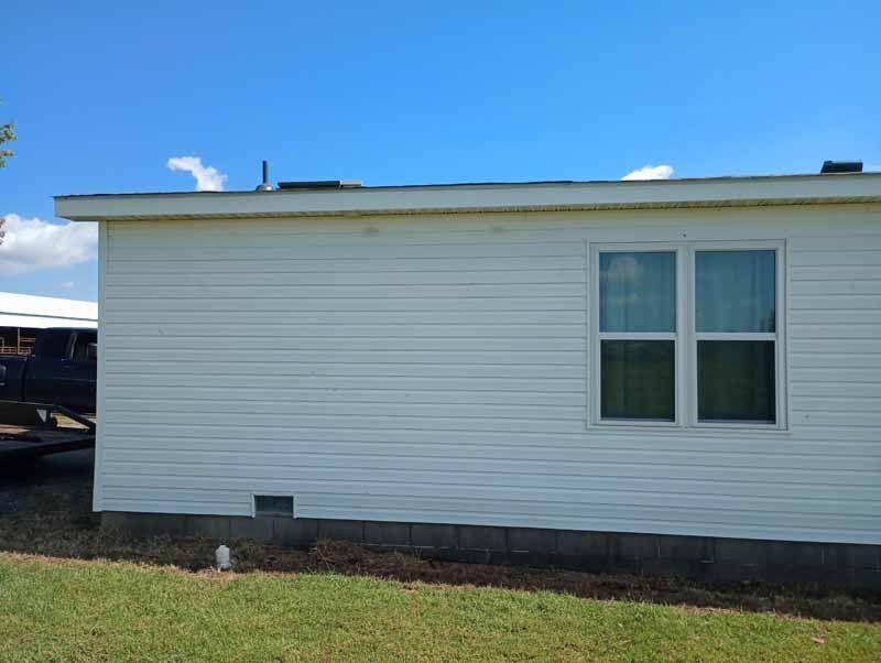 White house exterior with a window, against a blue sky.