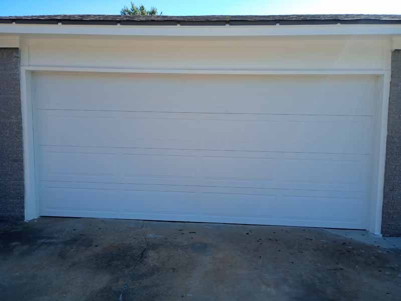 White garage door, horizontal paneling, with white trim and gray brick.
