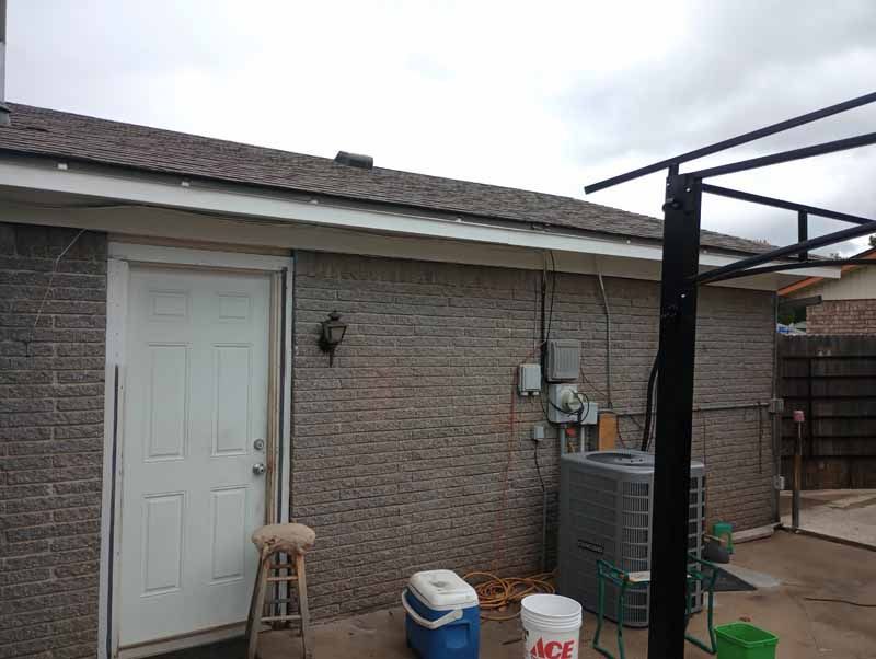 Backyard of a building with a white door, brick walls, and air conditioning unit.