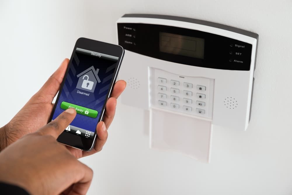 A Person is Holding a Cell Phone in Front of a Security System — BNCC Security Services in Port Macquarie, NSW