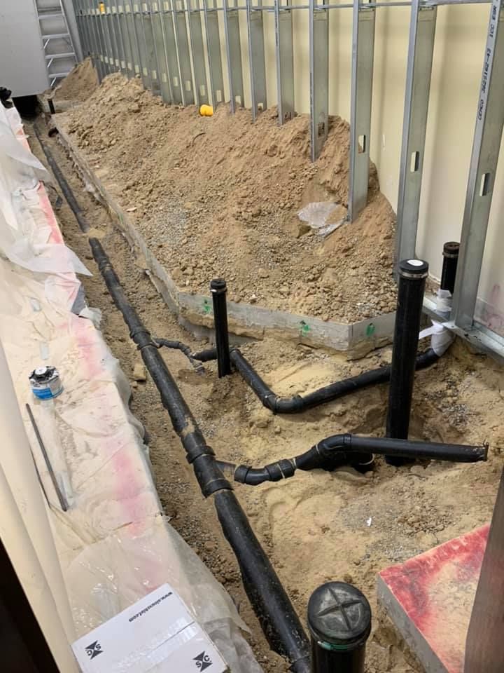 A bunch of pipes are laying in the dirt.
