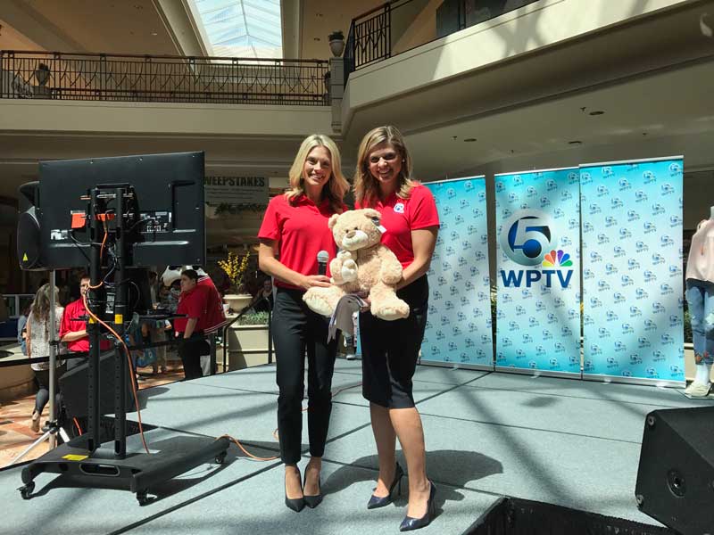 Ashley Hinson [left] and Ashleigh Walters [right] of WPTV 5 with Buddy Bear® at the back to School Expo