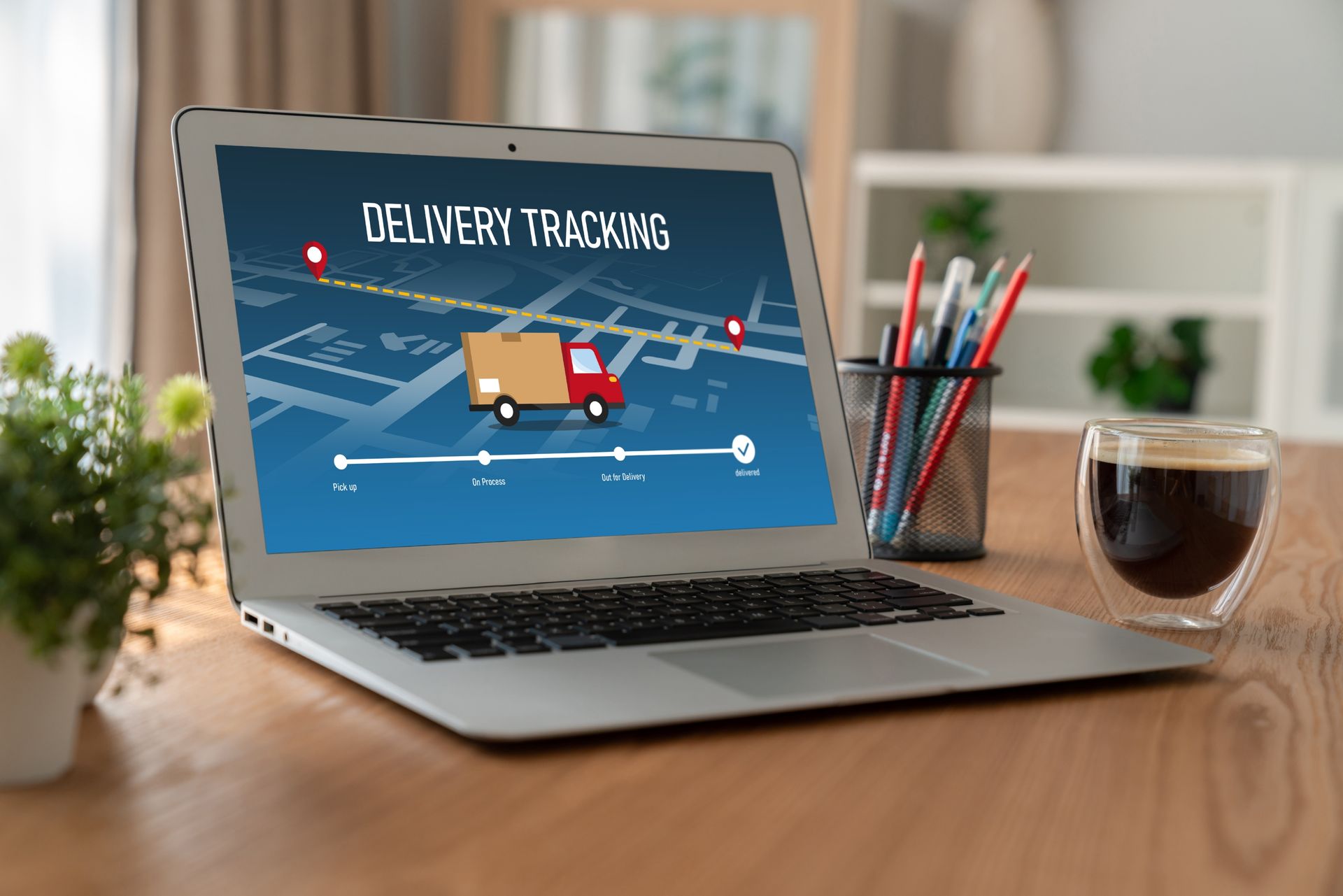 A laptop computer is sitting on a wooden desk with a delivery truck on the screen.