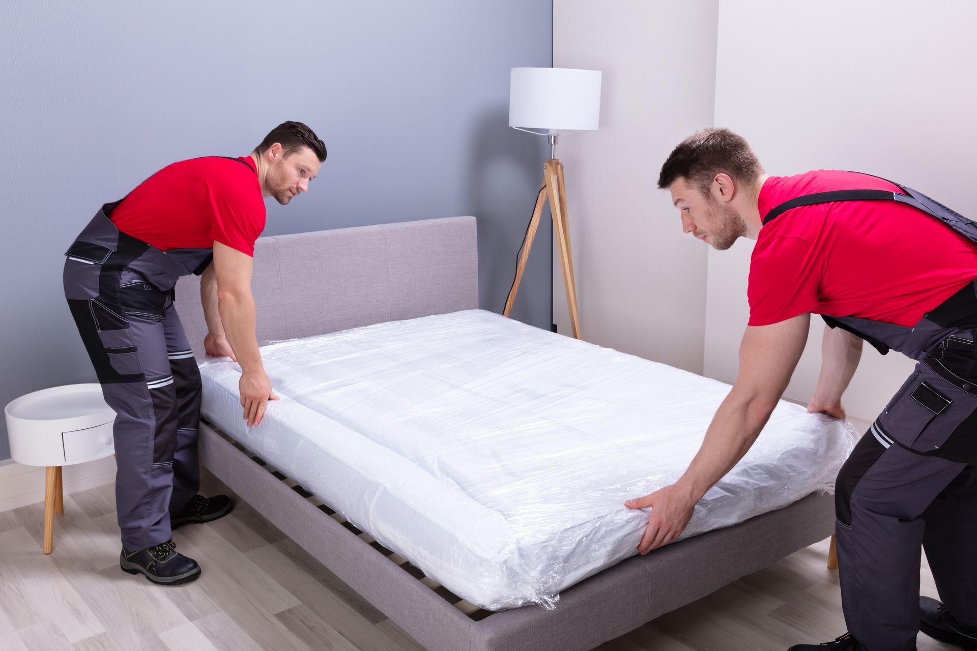 two men are moving a mattress in a bedroom .