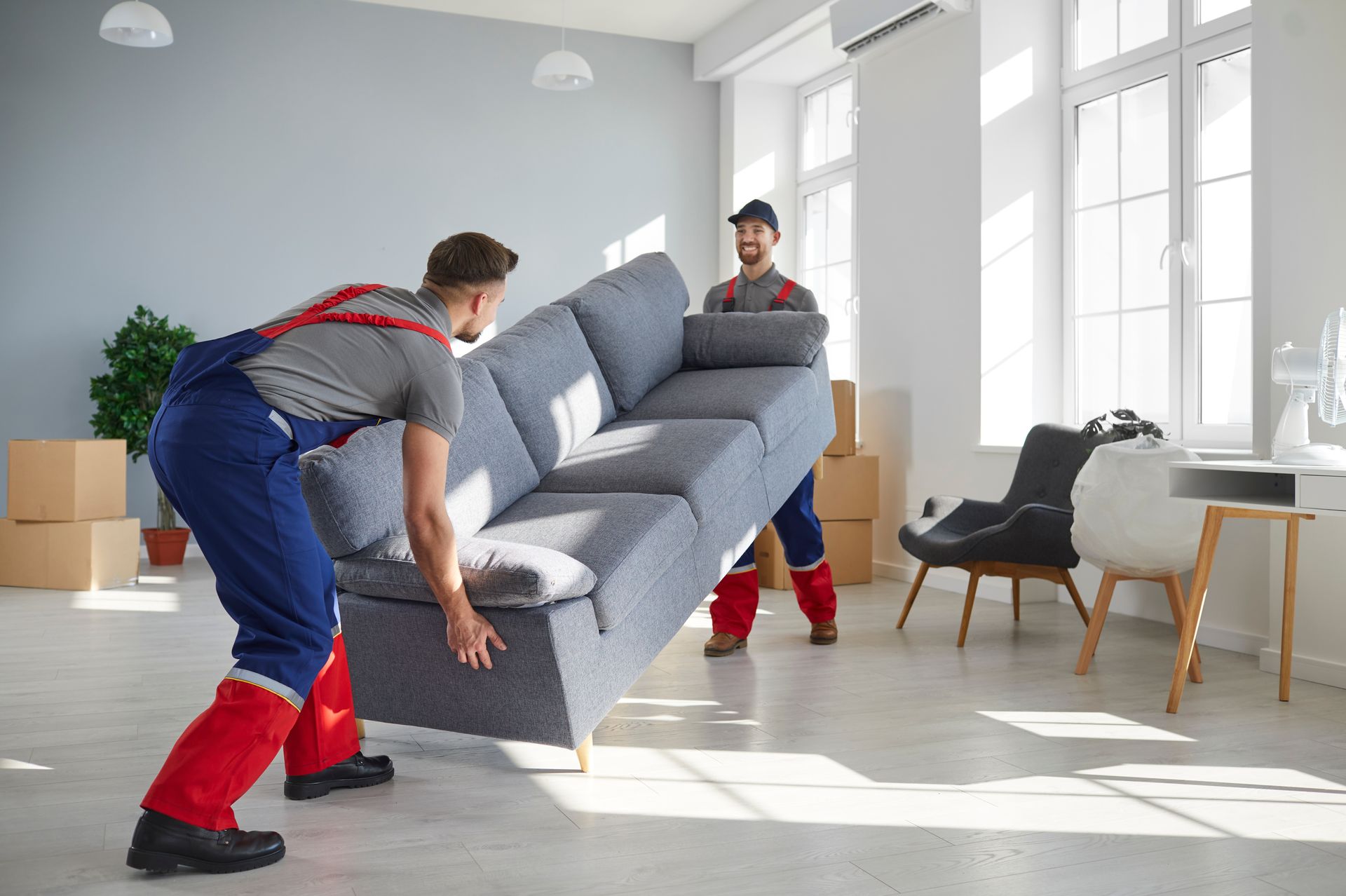two men are carrying a couch in a living room .