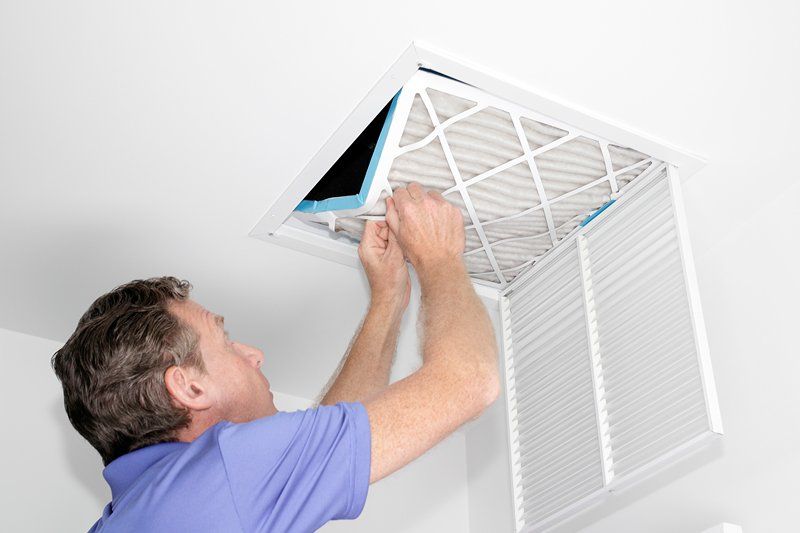 Man Removing Dirt On The Air Filter — Naples, FL — Mercury Rising HVAC Inc.