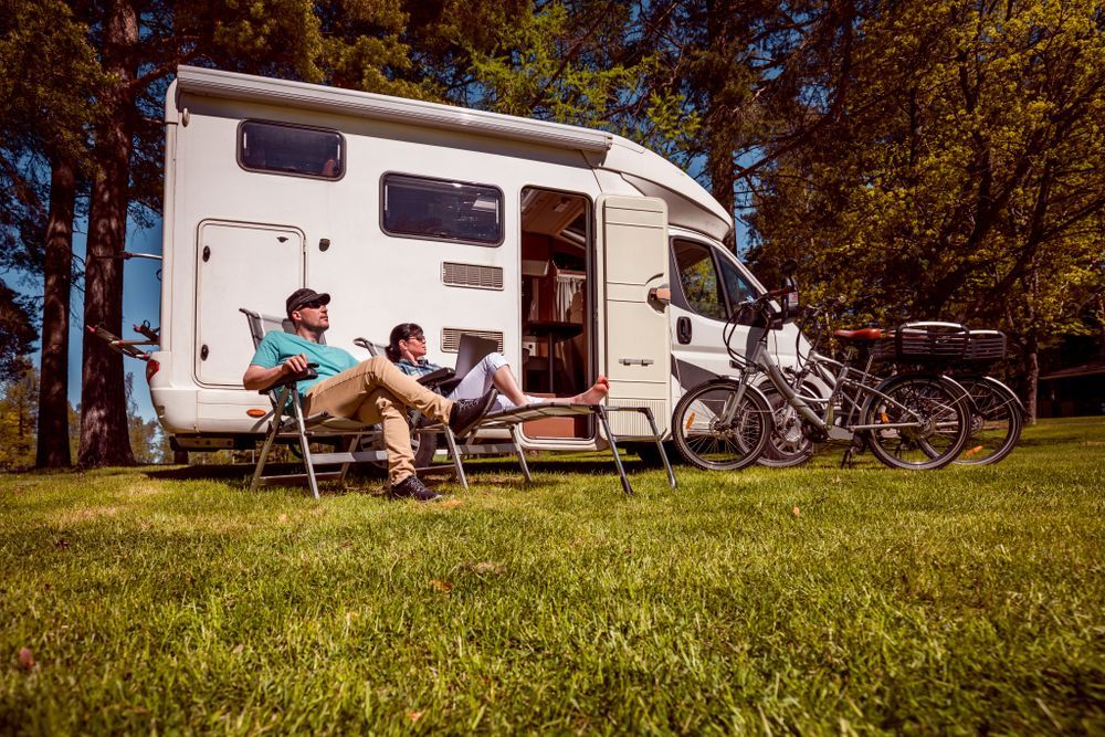 Two People Relax in Chairs Next to a White RV — Lakeside Gas Fridges In Argenton, NSW