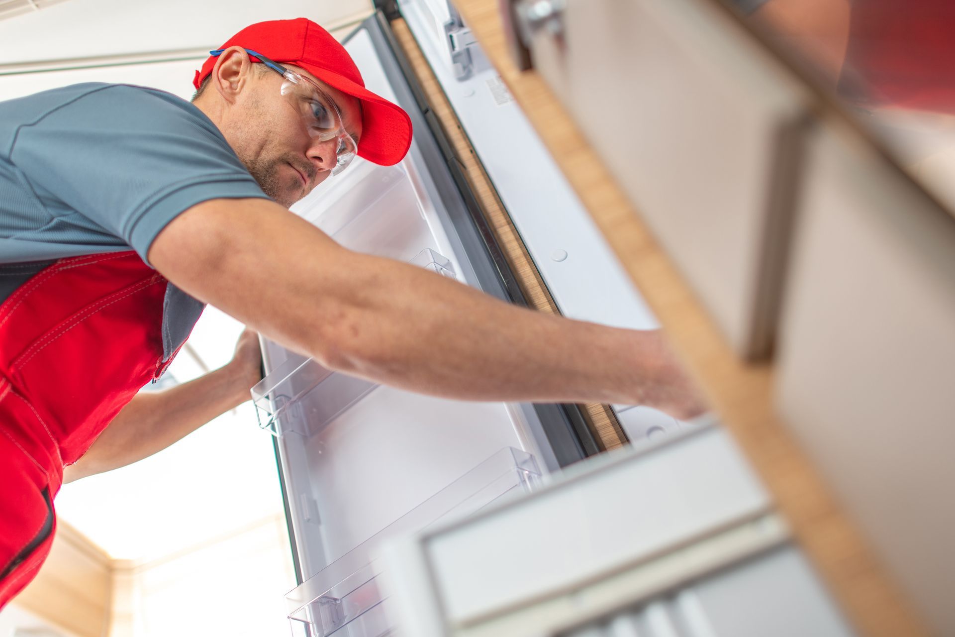 Person in Red Cap and Overalls Installs Something — Lakeside Gas Fridges In Argenton, NSW