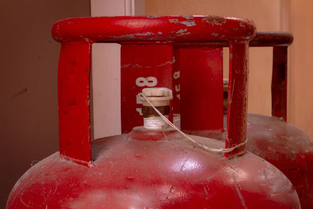 Red Propane Tanks with Metal Handles and White Valve Seals — Lakeside Gas Fridges In Cessnock, NSW