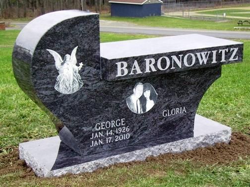 a park bench sits on a grassy hill under a tree