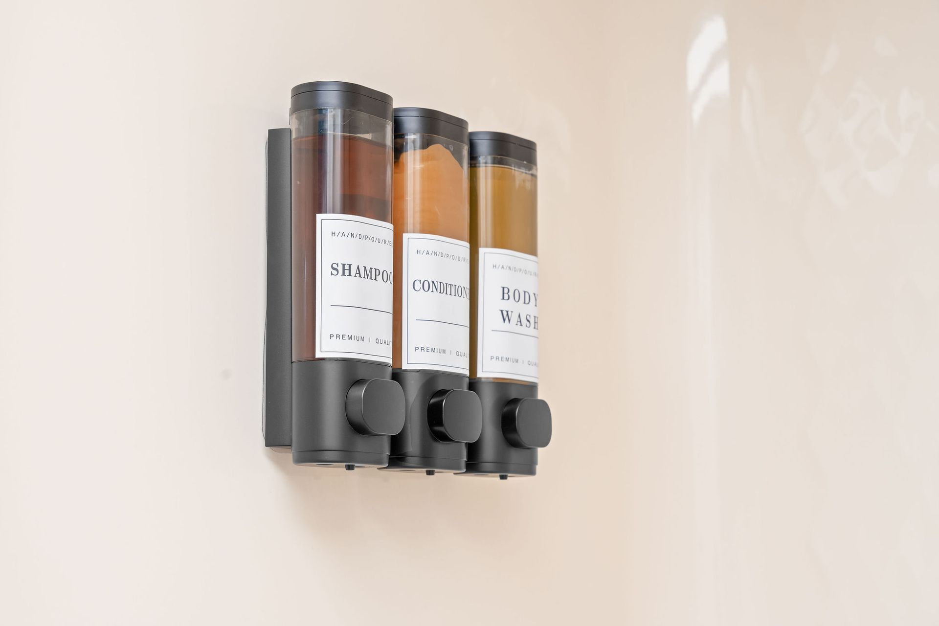 Three soap dispensers are hanging on a wall.