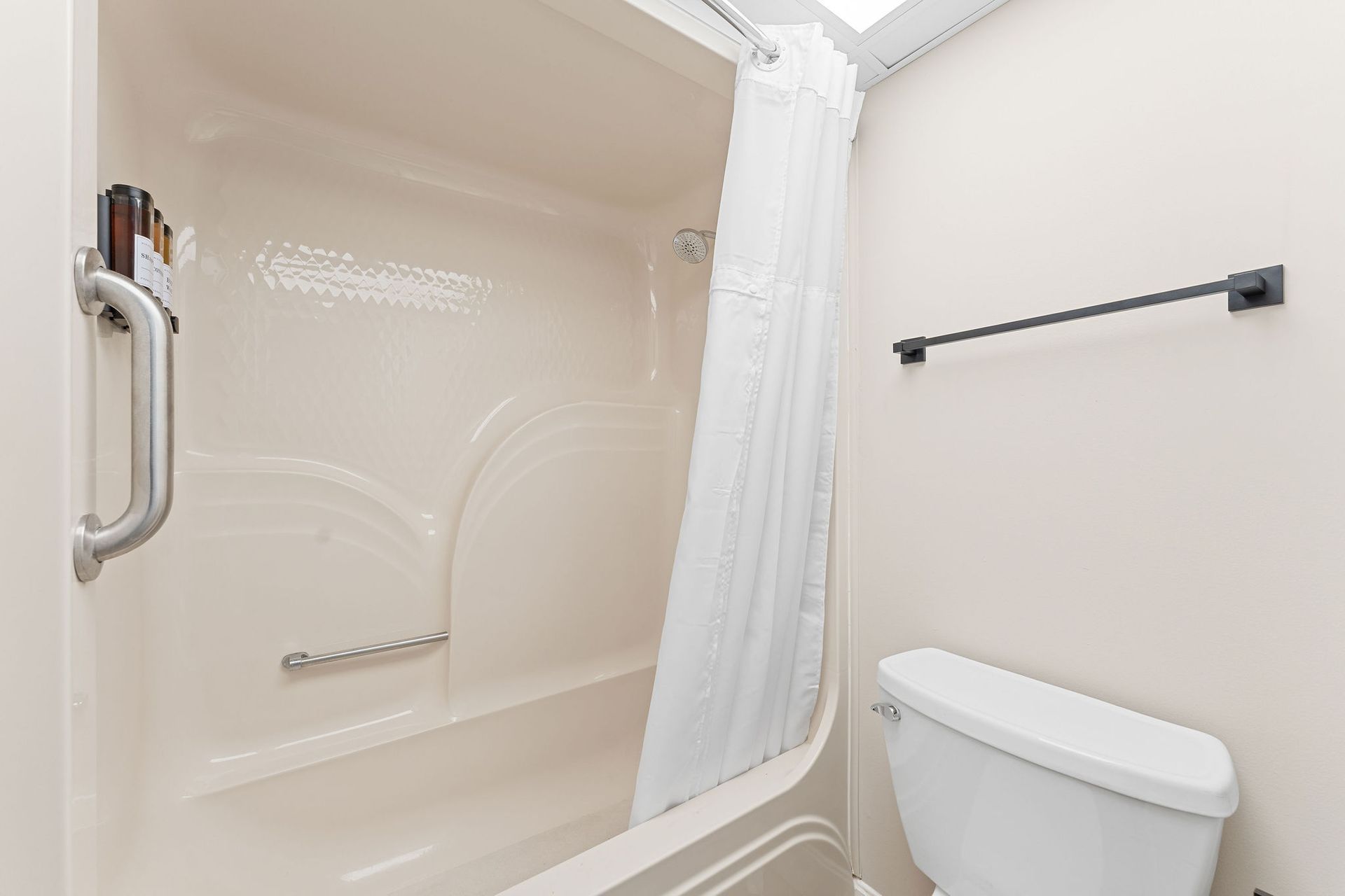 A bathroom with a tub , toilet , and shower curtain.