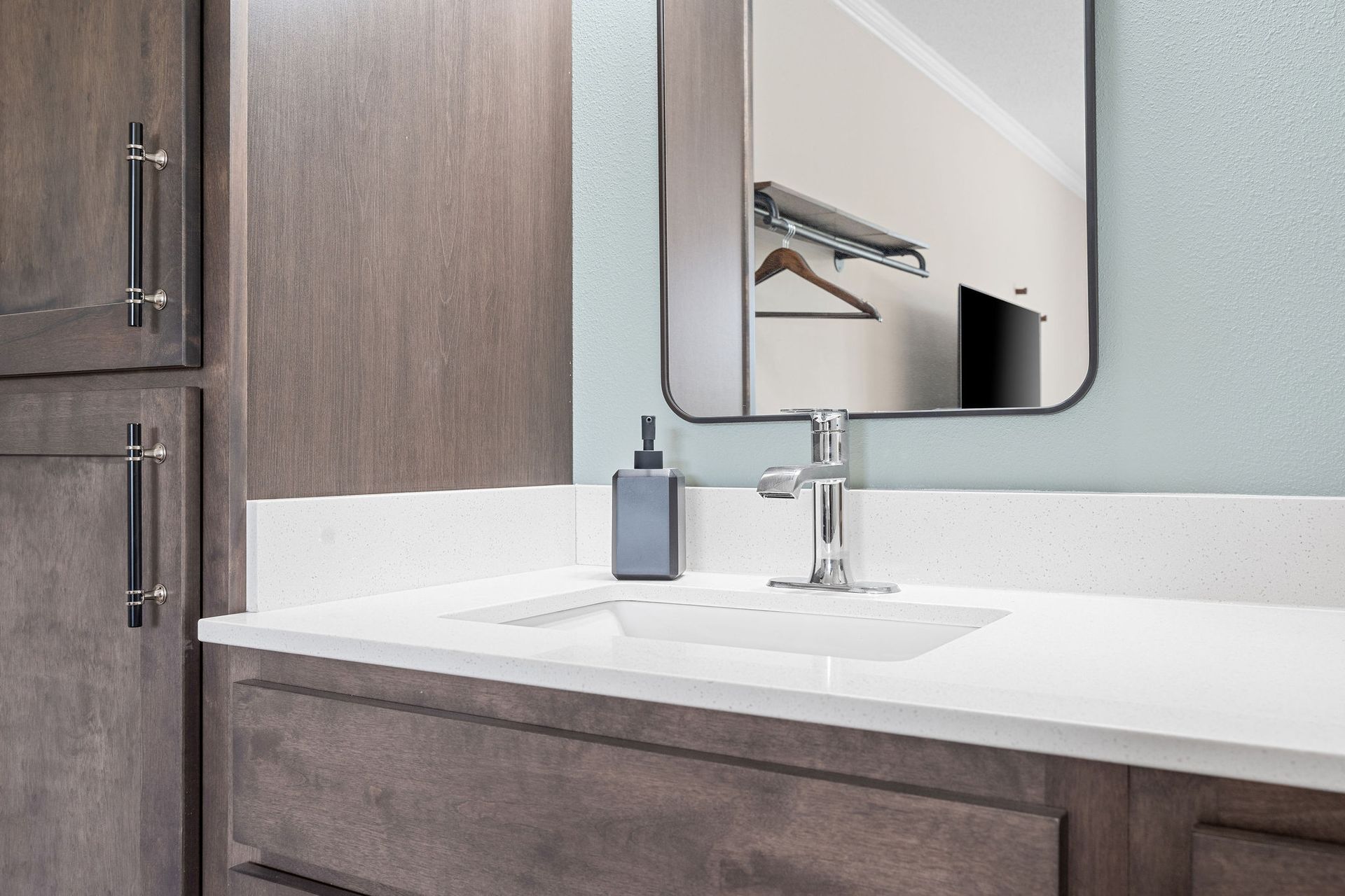 A bathroom with a sink , mirror and cabinets.