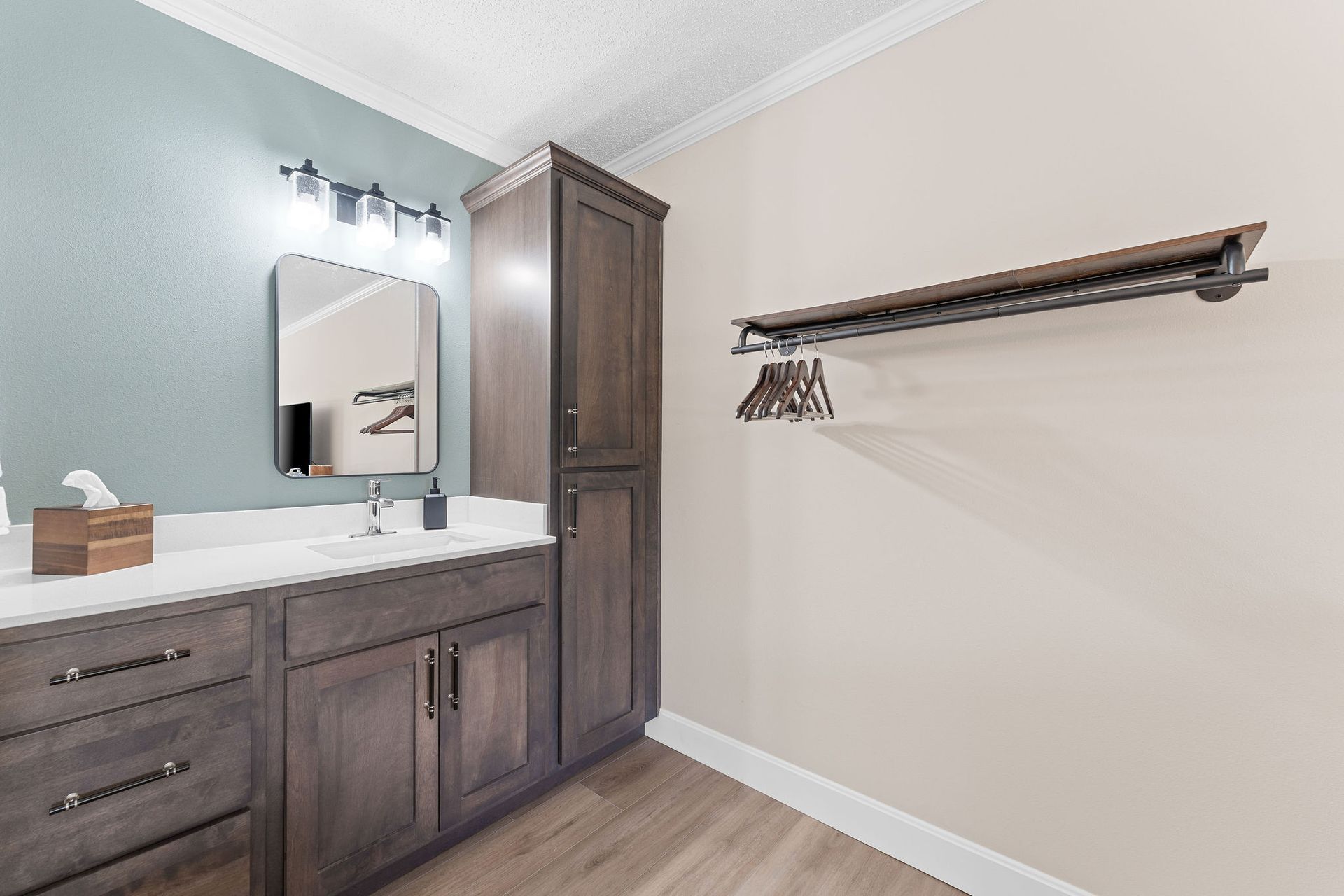 A bathroom with two sinks , a mirror and a clothes rack.